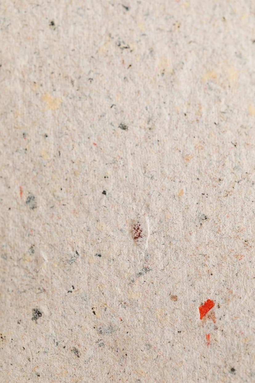 A sheet of recycled handmade paper flecked with small bits of colour