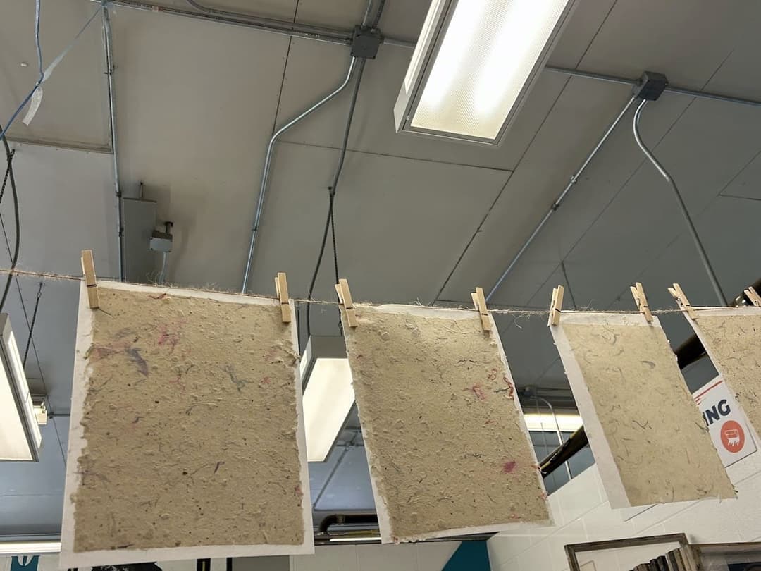 Handmade paper made from recycled paper pulp and dried flowers, hung on a line to dry