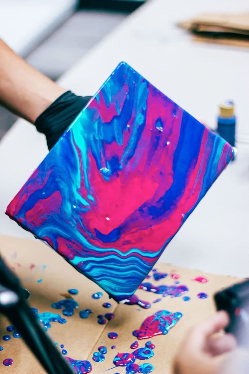 Poured acrylic paint running across a board, the same fluid-art technique used on paper